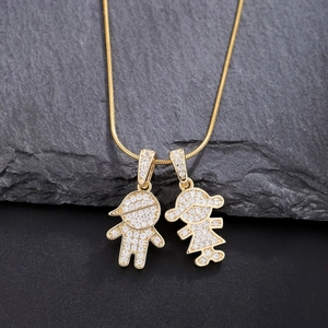Detailed shot of gold snake chain necklace with boy and girl pendants on dark rock