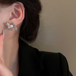 Detail of silver bow earrings with pearl tassel worn by model against soft background