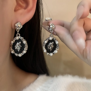 Détail macro de boucles d'oreilles portrait en argent avec bordures perlées gothiques