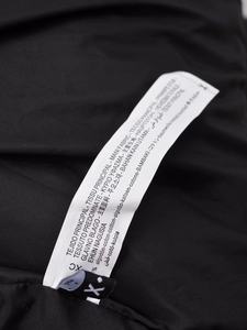 Detailansicht des weißen Pflegeetiketts auf schwarzem Baumwollstoff mit Materialangaben