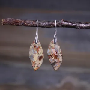 Close-up of leaf-shaped teardrop earrings with colorful stone texture on a branch