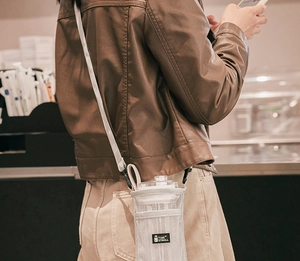 White mesh bottle carrier with adjustable shoulder strap worn by a person in a brown jacket