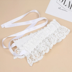 Detail of white lace waist belt featuring elegant silk ribbons on a beige background