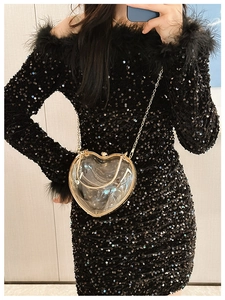 Close-up of a clear heart-shaped acrylic bag with gold metal frame and chain strap