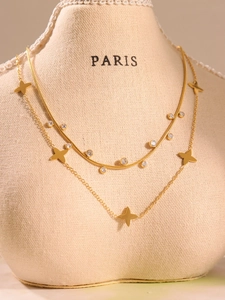 Detail of layered gold clover necklace with snake chain and star pendants on a bust