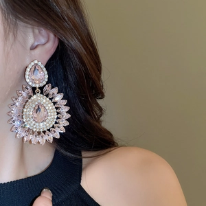 Macro detail of champagne pink teardrop earrings with crystals worn by a model