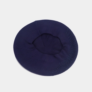 Détail du béret en maille marine avec des perles radiales élégantes sur le côté du bonnet