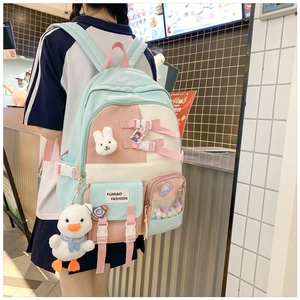 Detailed view of tricolor school backpack with plush pendants and multi-pocket structure