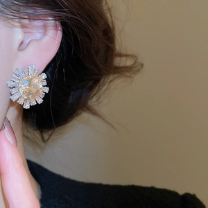 Detail of sunburst champagne zircon stud earring on ear in warm vintage setting