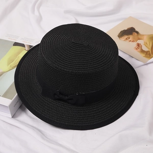 Close-up of a black flat-top straw boater hat featuring a stylish grosgrain ribbon bow