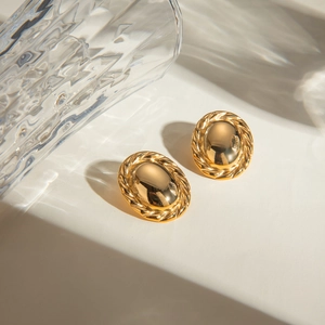 Gold oval earrings with smooth center and rope edge design on a minimal background