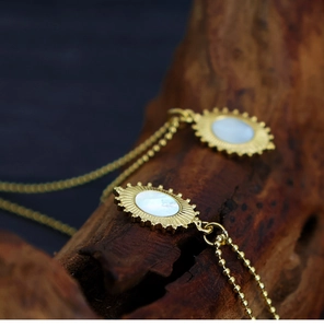 Macro shot of gold oval pendant with mother of pearl inlay on bohemian beaded chain