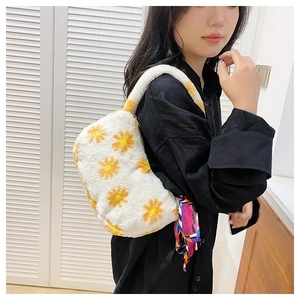 Detail view of a white plush underarm bag with yellow daisy embroidery and a colorful scarf