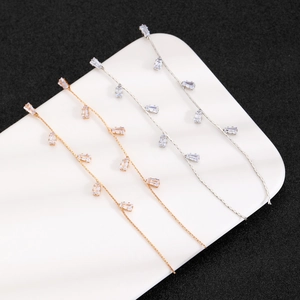Macro detail of long tassel earrings with rectangular zircons on a white ceramic plate