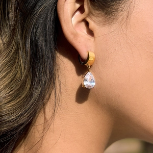 Gros plan d'élégantes boucles d'oreilles en acier doré avec zircon en goutte d'eau