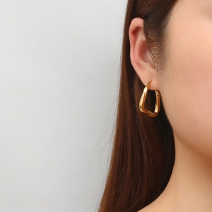 Elegant gold titanium steel twisted square earrings worn by a model on white background