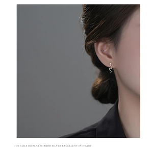 Macro detail of snake-shaped silver stud earring on ear showing high-mirror metallic finish