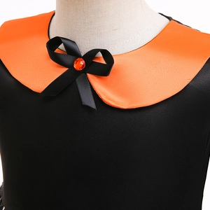 Detail of Halloween girl's dress featuring orange collar with black bow and gemstone