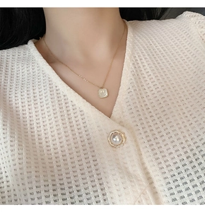 Detail of a gold square shell pendant with a smiley face on a fine titanium steel chain