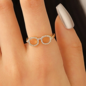 Macro shot of a creative gold-tone glasses ring with micro-pave crystals on female finger
