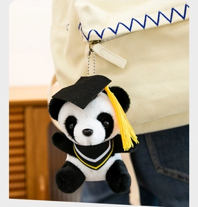 Detailed view of a plush panda keychain wearing a graduation cap and gown on a backpack.