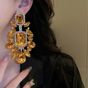 Macro shot of amber yellow teardrop earrings with crystal embellishments on model