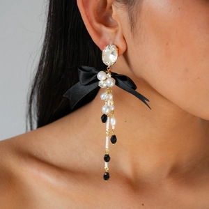 Macro shot of elegant bow earrings with pearls and crystals on a model for a luxury look