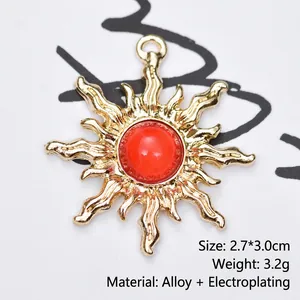 Detailed macro view of gold-plated sunburst pendant with red gemstone, size 2.7x3.0cm