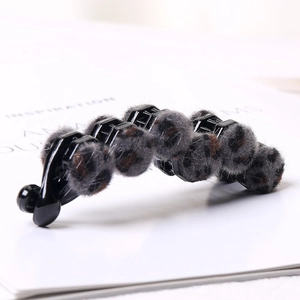 Detail shot of a banana hair clip featuring grey and brown leopard print plush beads