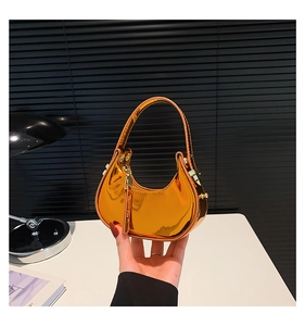 Detailed view of a gold metallic crescent handbag featuring a glossy mirror finish surface
