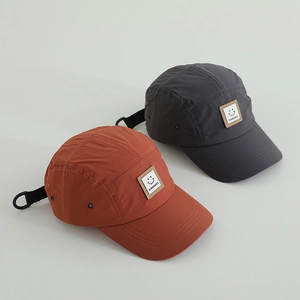 Detail of 5-panel camping hats in grey and orange with smile kindness logo patch