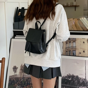 Modella che indossa mini zaino nero in ecopelle con patta e coulisse regolabile