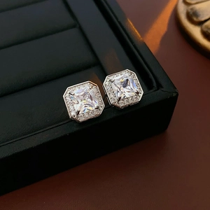 Gros plan de boucles d'oreilles carrées en argent avec zircons sur un écrin en cuir noir