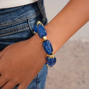 Close-up of glittery blue acrylic beads and gold geometric charms on a beaded bracelet