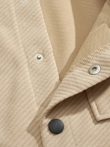 Close-up of beige twill fabric texture with metal snap buttons and black main button