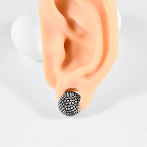 Detail of stainless steel ear weight plug with punk style cone studs on a silicone ear model