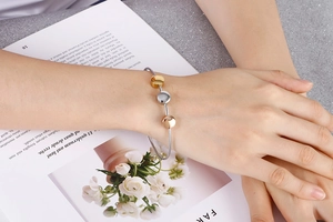 Close-up of tricolor steel wire bracelet with gold, silver, and rose gold beads on a model