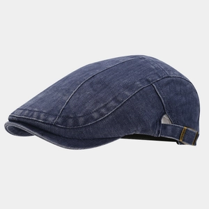 Macro detail of dark blue washed denim flat cap showing brass buckle and stitching