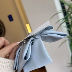 Close-up of a light blue silk bow hair clip with a spring fastener and satin texture
