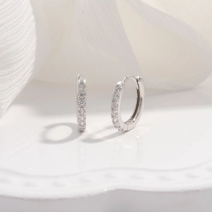 Macro view of sterling silver hoop earrings with cubic zirconia on white fabric