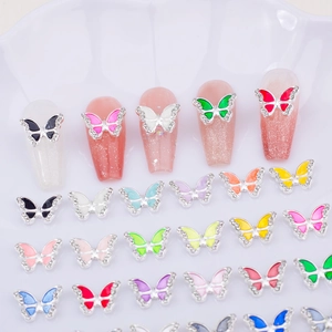 Macro view of butterfly nail charms with colorful enamel wings and small rhinestones