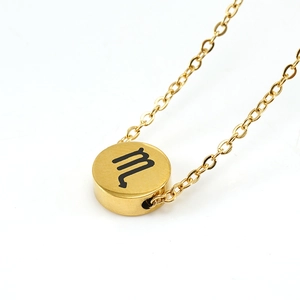 Macro detail of golden round pendant necklace featuring engraved black Scorpio zodiac symbol