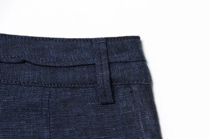 Makrodetail des dunkelblauen Jeansbunds mit Gürtelschlaufen und robuster Doppelnahtführung