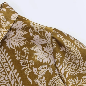 Détail macro de la chemise en satin jaune moutarde avec motifs paisley et coutures précises