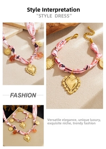 Détails d'un collier foulard en soie rose avec pendentifs cœur et soleil dorés