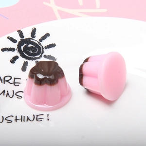 Pink and chocolate resin jelly pudding charms for DIY crafts on a white ceramic plate