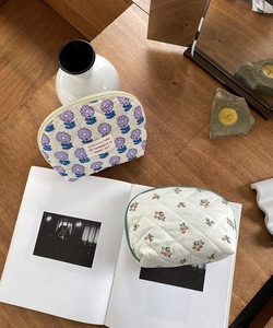 Quilted floral and cherry makeup bags on a wooden table for organized storage