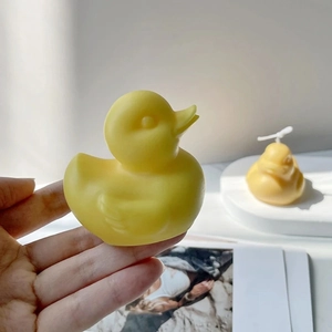 A detailed view of a handcrafted yellow duck-shaped aromatherapy candle held in a hand