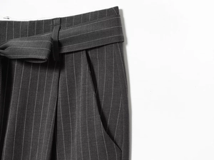 Detail of dark grey striped wide-leg pants featuring a self-tie belt and waist loops