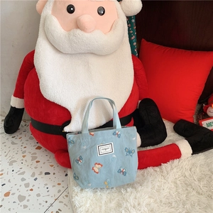 Détail de broderie papillon et étiquette tissée sur un sac cabas en toile bleu clair